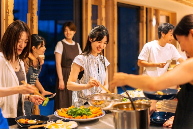 町の人と参加者で料理を囲む夜の風景